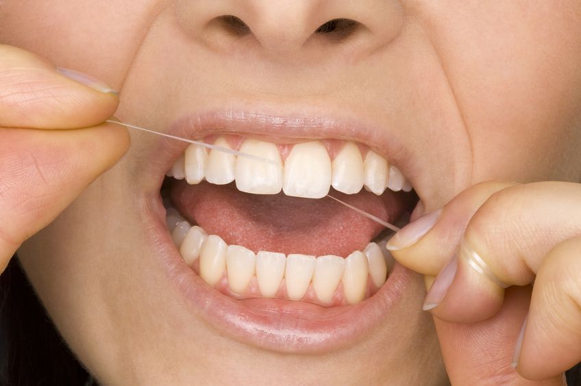 Close-up of person flossing their teeth.