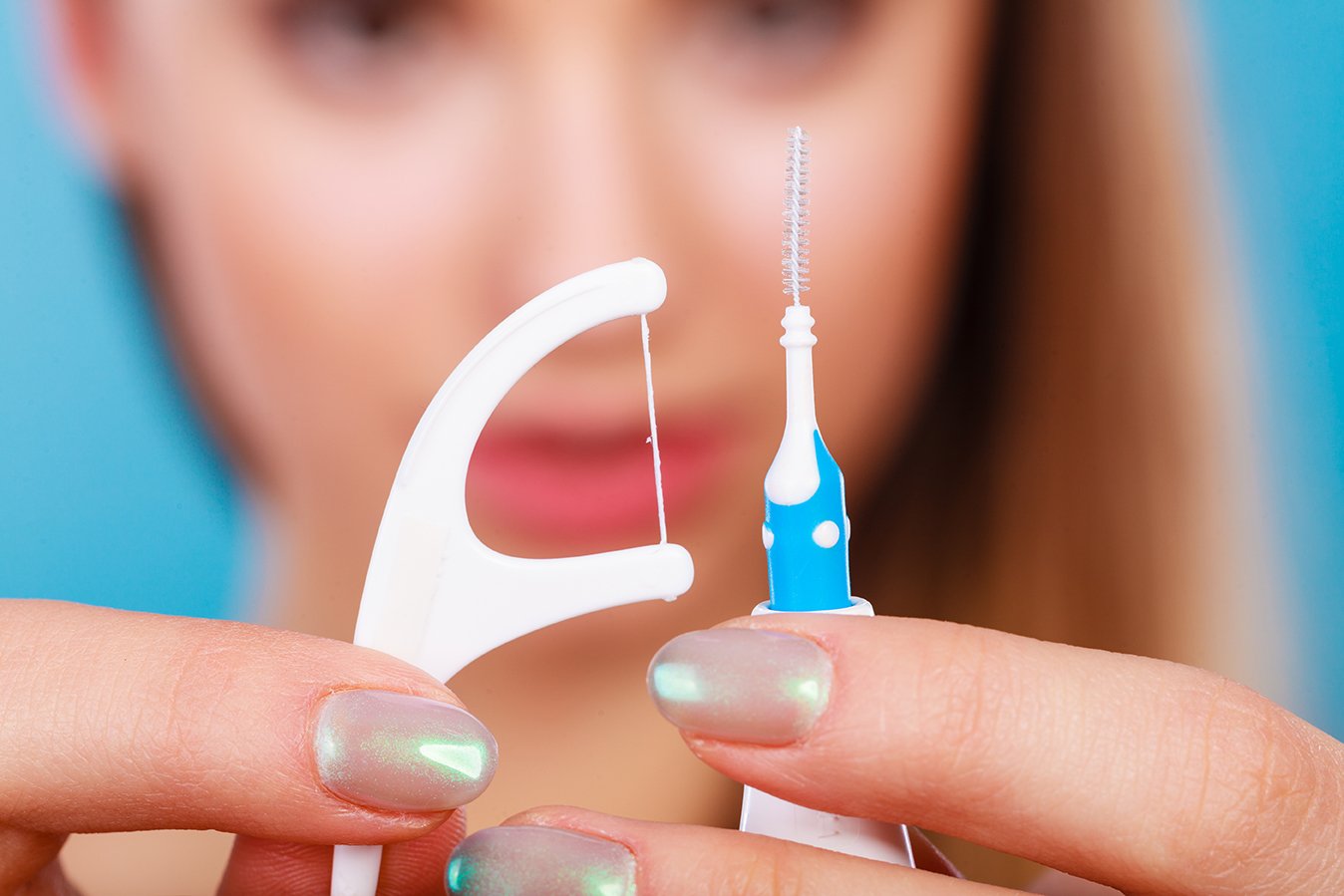 Woman holding small toothbrush and dental floss.