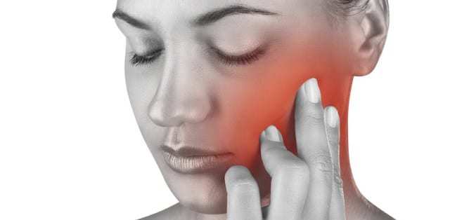 Black and white image of woman holding her hand up to her jaw.