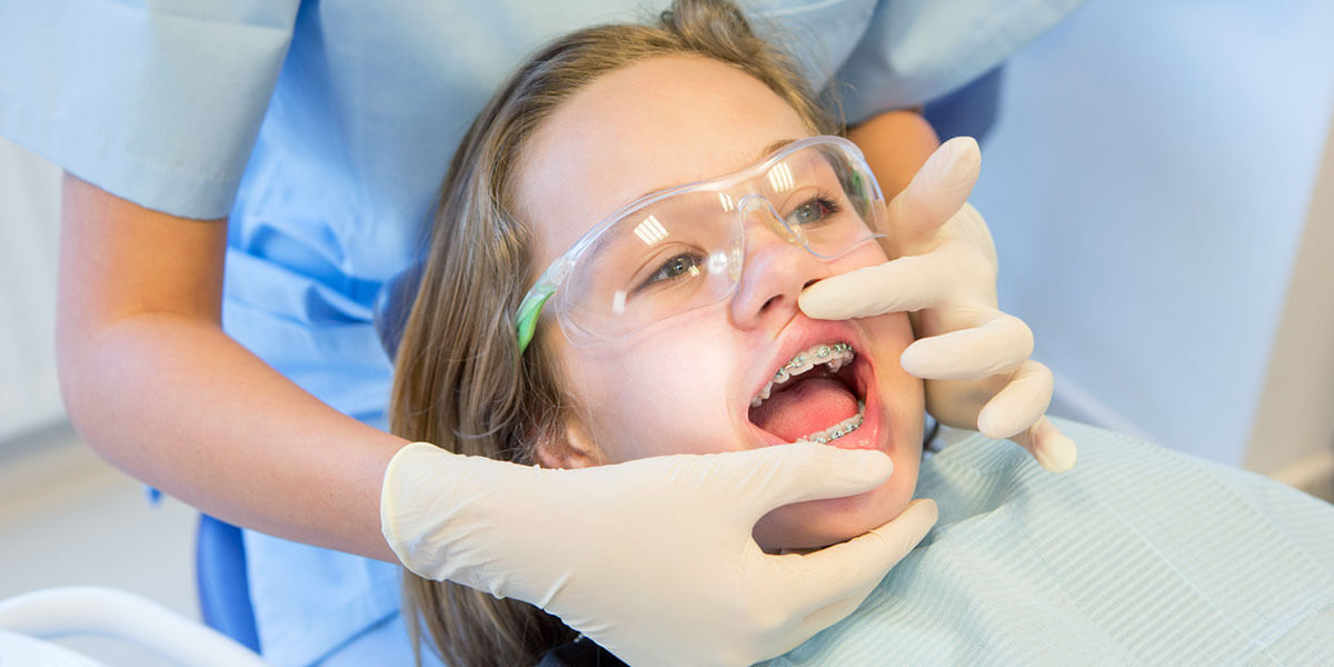 Dental assistant in blue scrubs preparing for a procedure with gloved hands.