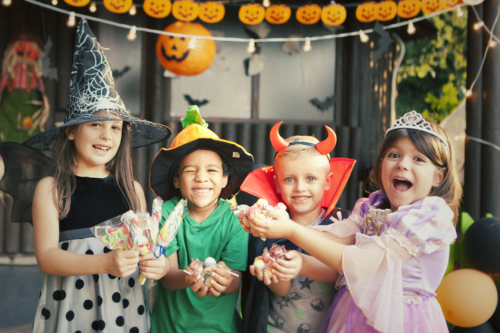 Group of children dressed up for Halloween holding candy.