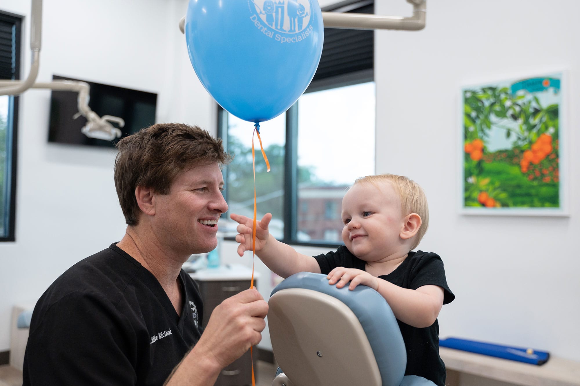 A baby reaches for a balloon at the dentist's office