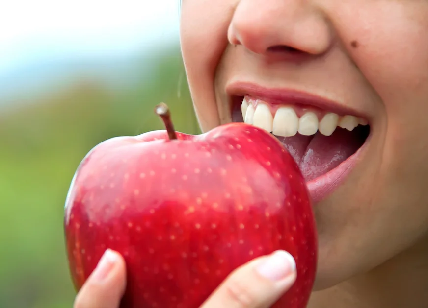 Person biting into a red apple