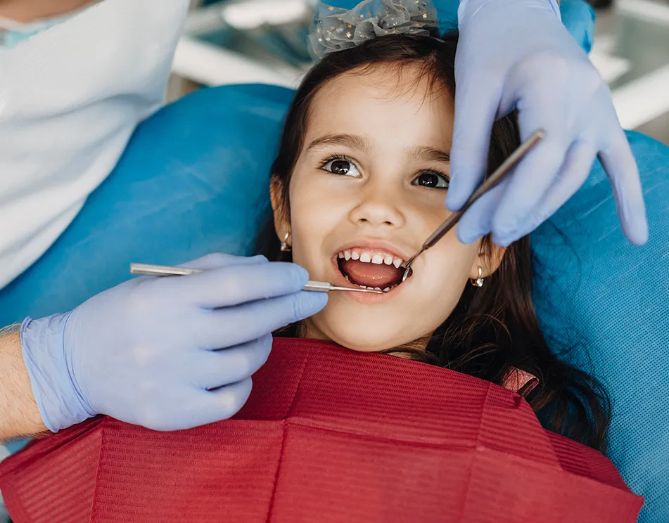 Young girl in dental chair getting teeth examined