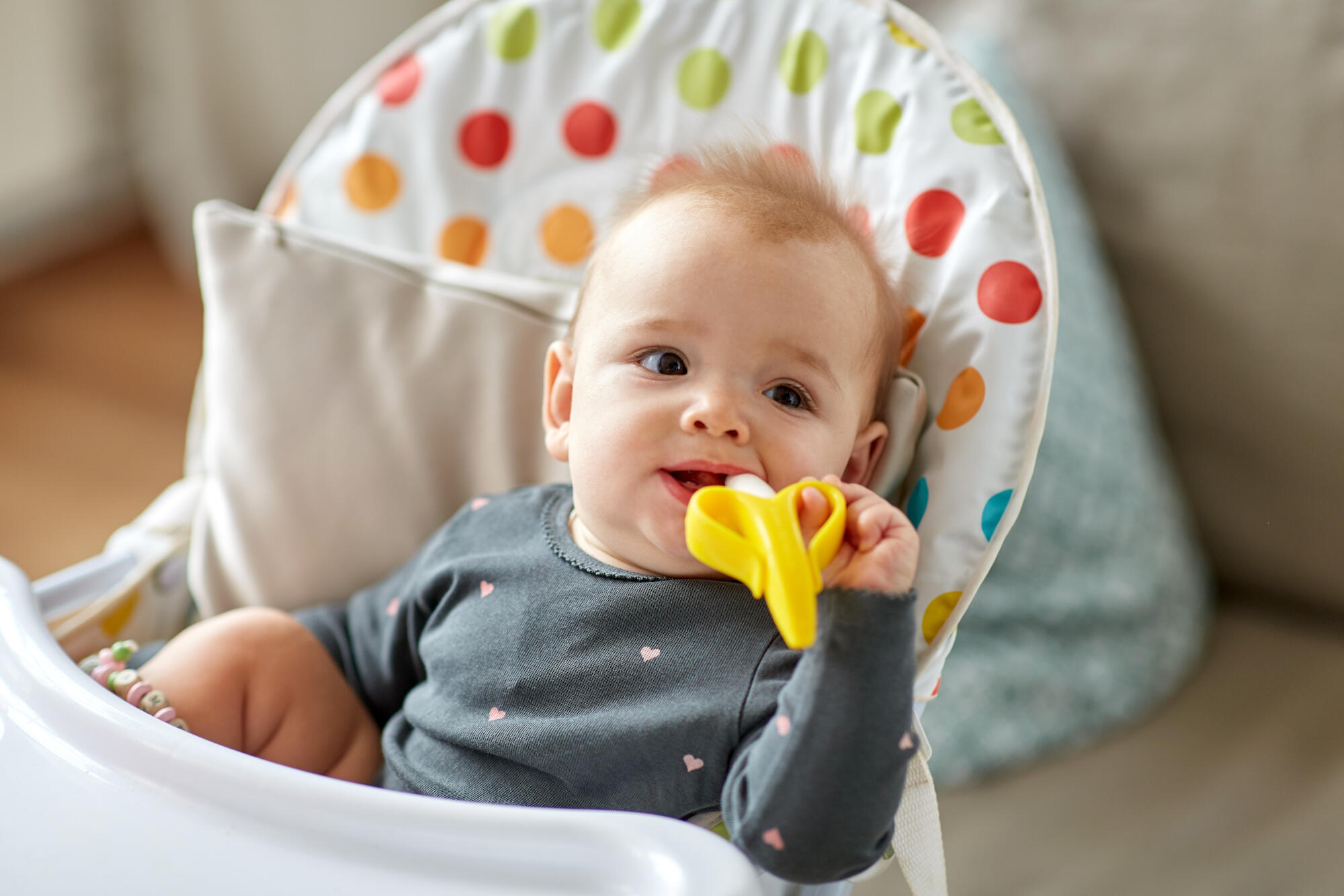 Baby teething on yellow toy