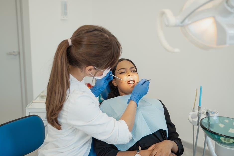 Female dentist looking at patients teeth as they sit in the dental chair