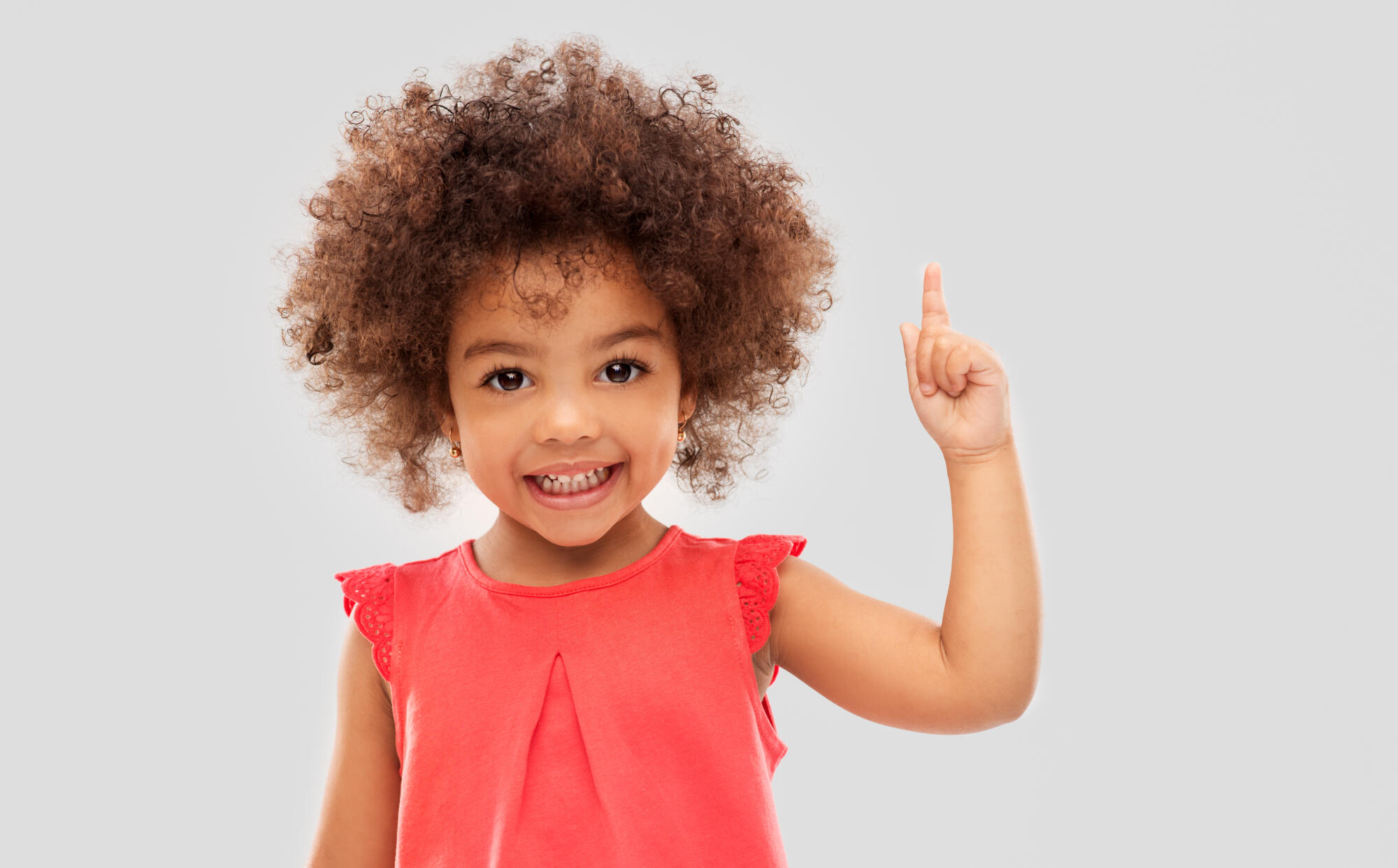 Little girl in a red shirt pointing a finger up