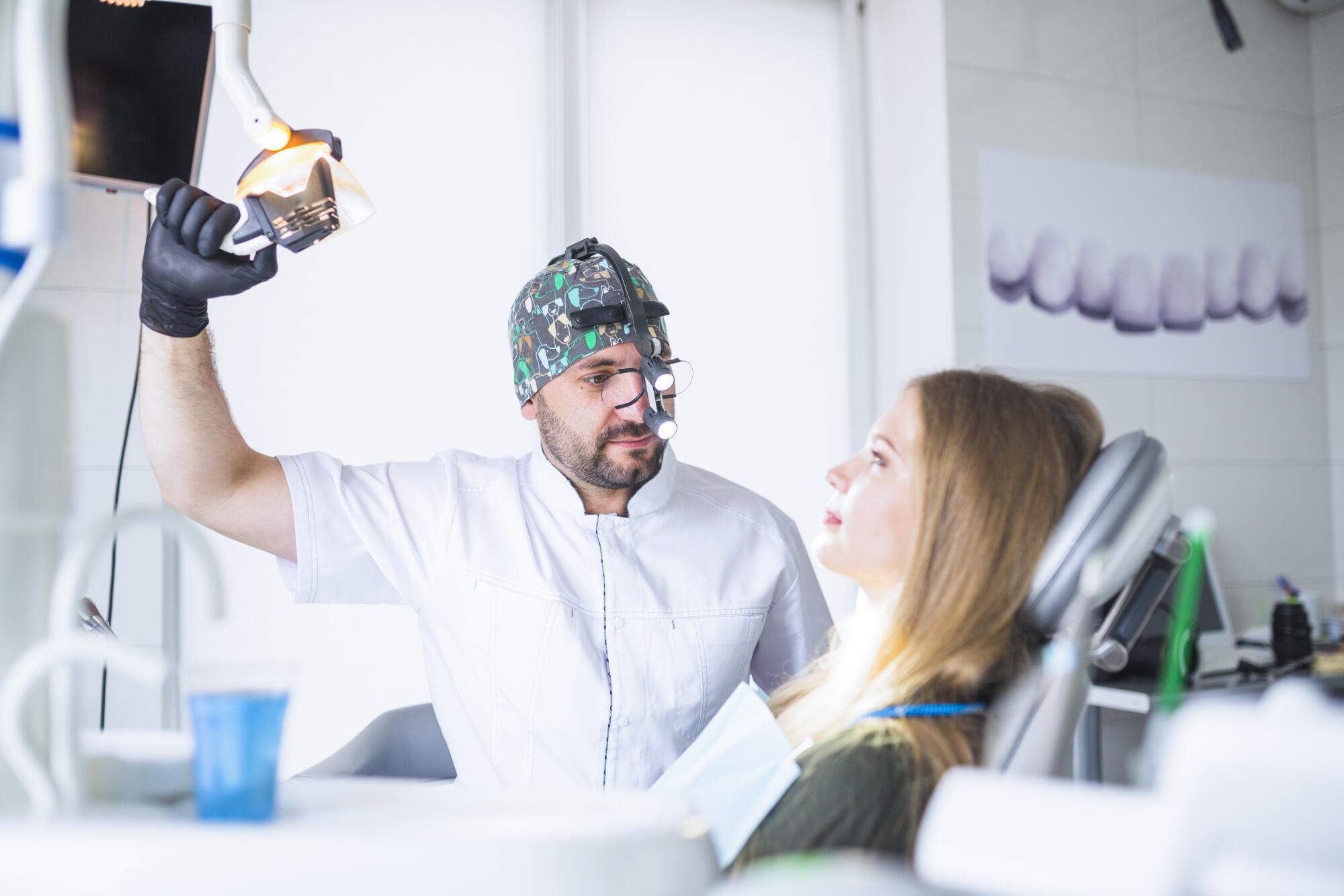 Women in dental chair with mail dentist inspecting her teeth